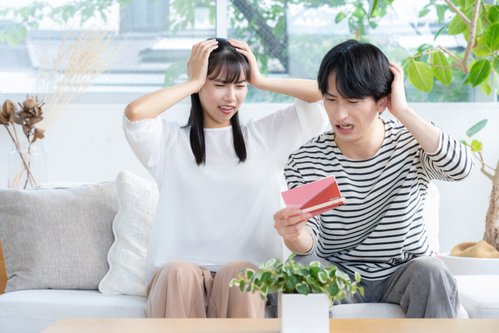 通帳を見て頭を抱えるカップル
